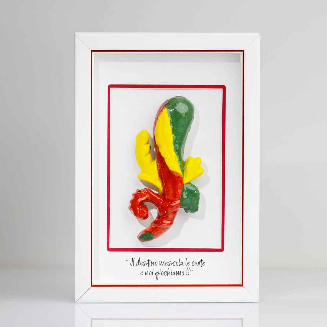 Quadro con cornice contenente una riproduzione tridimensionale in ceramica dell'Asso di Bastoni delle carte napoletane. Il bastone nodoso è colorato in verde, giallo e rosso, con una forma ricurva alla base. In basso compare la scritta in corsivo: "Il destino mescola le carte e noi giochiamo!!". Il bordo interno della cornice è rosso