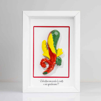 Quadro con cornice bianca contenente una riproduzione tridimensionale in ceramica dell'Asso di Bastoni delle carte napoletane. Il bastone nodoso è colorato in verde, giallo e rosso, con una forma ricurva alla base. In basso compare la scritta in corsivo: "Il destino mescola le carte e noi giochiamo!!". 