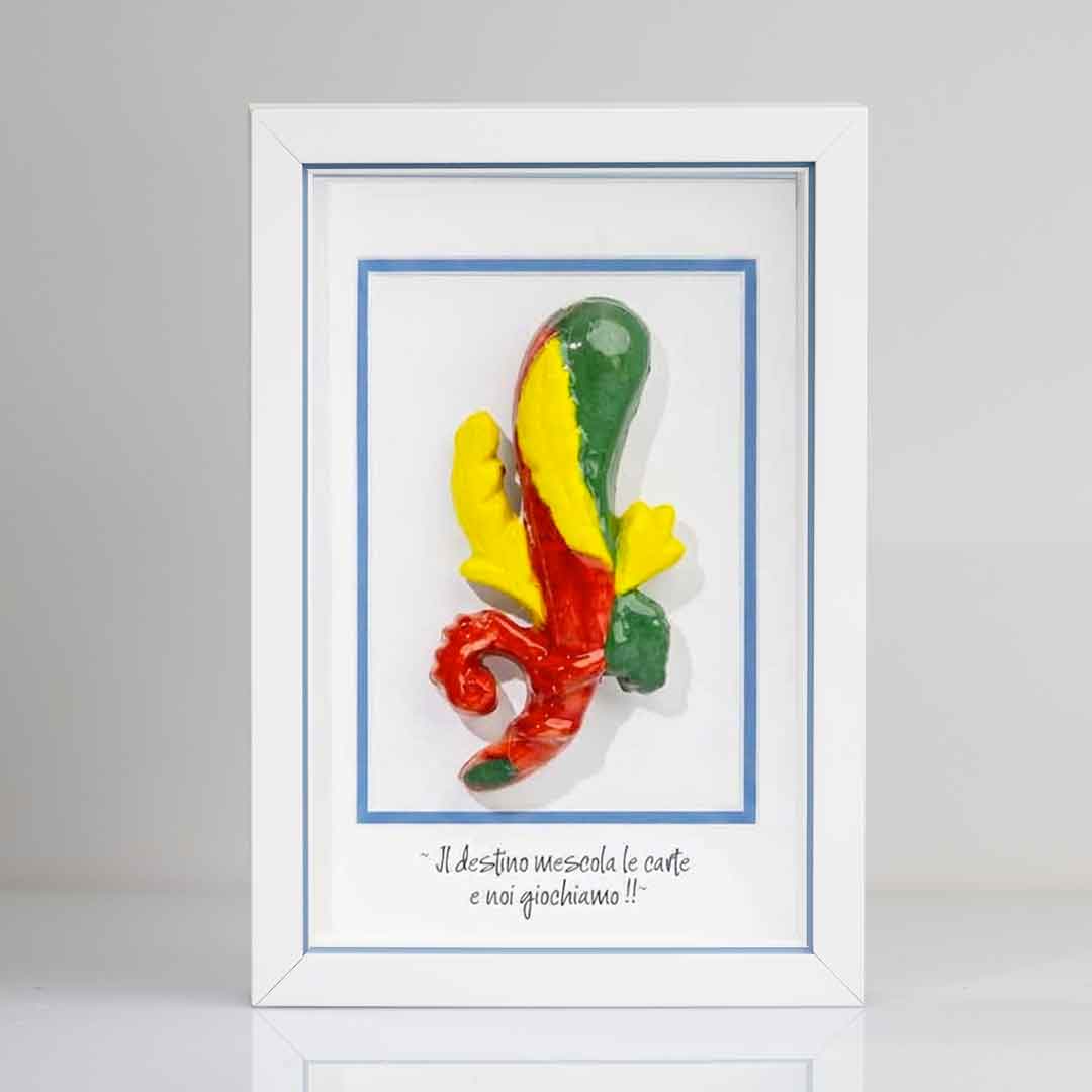 Quadro con cornice  contenente una riproduzione tridimensionale in ceramica dell'Asso di Bastoni delle carte napoletane. Il bastone nodoso è colorato in verde, giallo e rosso, con una forma ricurva alla base. In basso compare la scritta in corsivo: "Il destino mescola le carte e noi giochiamo!!". Il rigo interno della cornice è azzurro