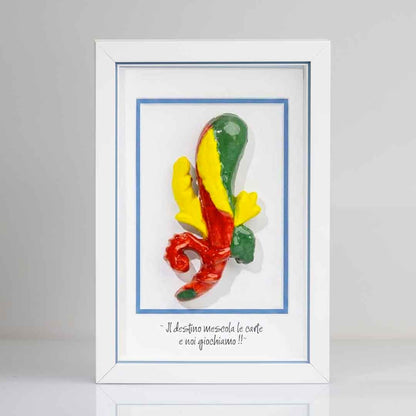 Quadro con cornice  contenente una riproduzione tridimensionale in ceramica dell'Asso di Bastoni delle carte napoletane. Il bastone nodoso è colorato in verde, giallo e rosso, con una forma ricurva alla base. In basso compare la scritta in corsivo: "Il destino mescola le carte e noi giochiamo!!". Il rigo interno della cornice è azzurro