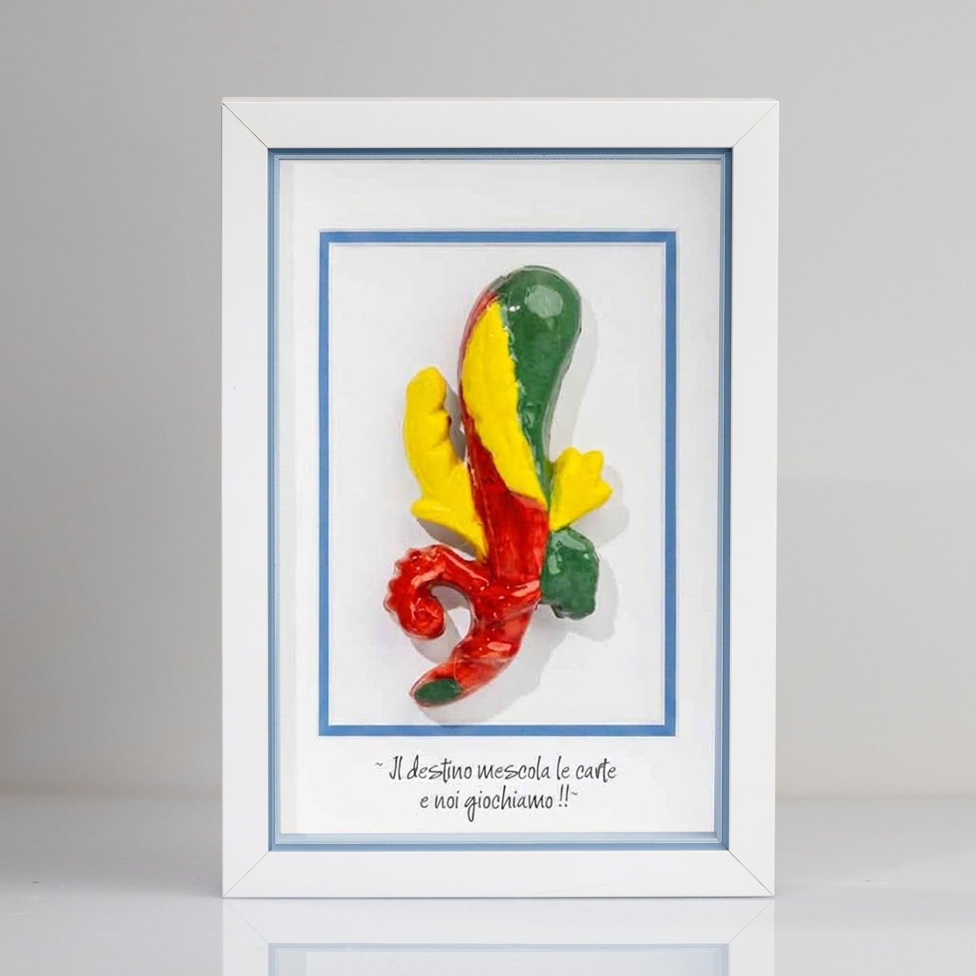 Quadro con cornice contenente una riproduzione tridimensionale in ceramica dell'Asso di Bastoni delle carte napoletane. Il bastone nodoso è colorato in verde, giallo e rosso, con una forma ricurva alla base. In basso compare la scritta in corsivo: "Il destino mescola le carte e noi giochiamo!!". Il bordo interno della cornice è azzurro