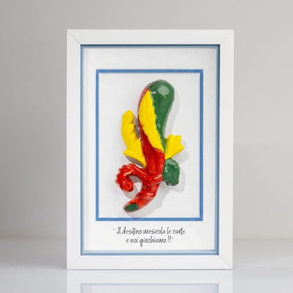 Quadro con cornice contenente una riproduzione tridimensionale in ceramica dell'Asso di Bastoni delle carte napoletane. Il bastone nodoso è colorato in verde, giallo e rosso, con una forma ricurva alla base. In basso compare la scritta in corsivo: "Il destino mescola le carte e noi giochiamo!!". Il bordo interno della cornice è azzurro